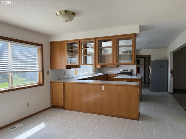 16117 NE 87th St, Vancouver, WA 98682 - kitchen with stainless steel appliances, a peninsula, brown cabinetry, and glass insert cabinets