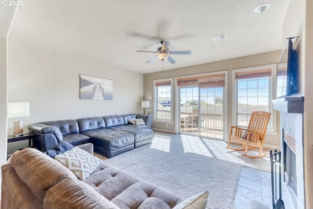 547 Front St, Rockaway Beach, OR 97136 - living room featuring a tile fireplace, ceiling fan, and a textured ceiling