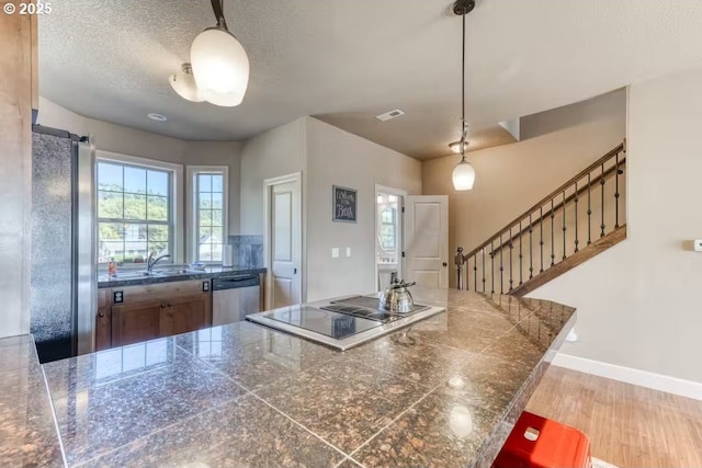 547 Front St, Rockaway Beach, OR 97136 - kitchen with kitchen peninsula, a textured ceiling, stainless steel appliances, sink, and decorative light fixtures
