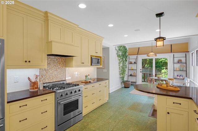 2603 NE 11th Ave, Portland, OR 97212 - kitchen with appliances with stainless steel finishes, cream cabinets, dark countertops, light flooring, and recessed lighting