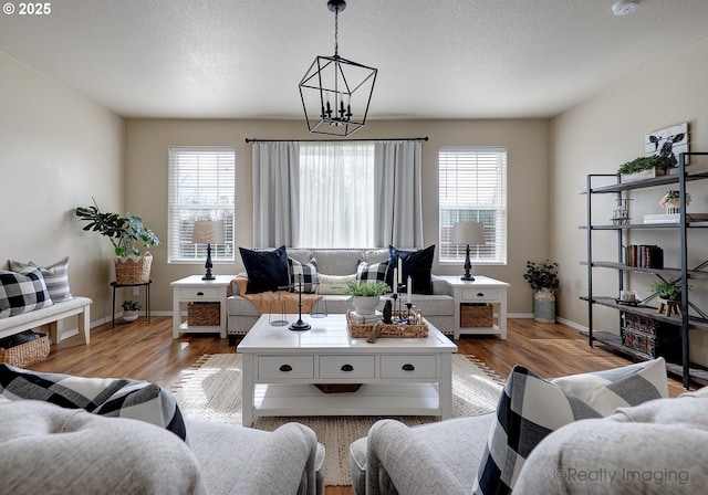 living room featuring light wood-style flooring, baseboards, and a textured ceiling