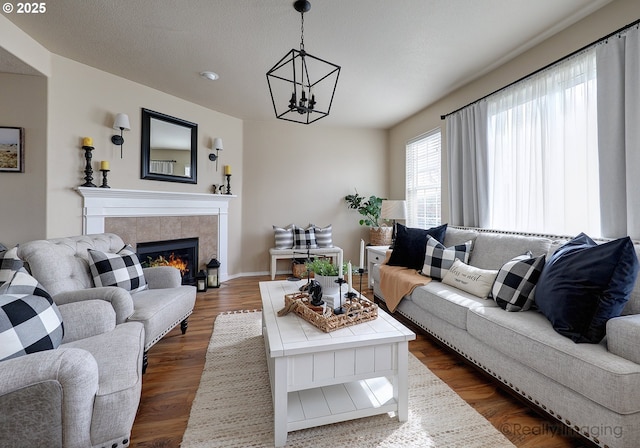 living area with a tiled fireplace, dark wood finished floors, and an inviting chandelier