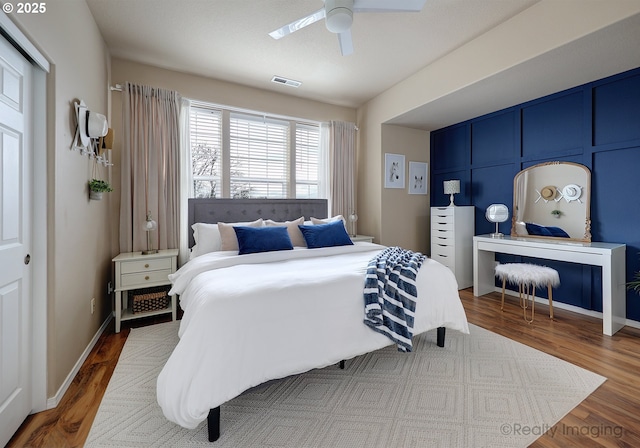 bedroom featuring visible vents, baseboards, ceiling fan, and wood finished floors