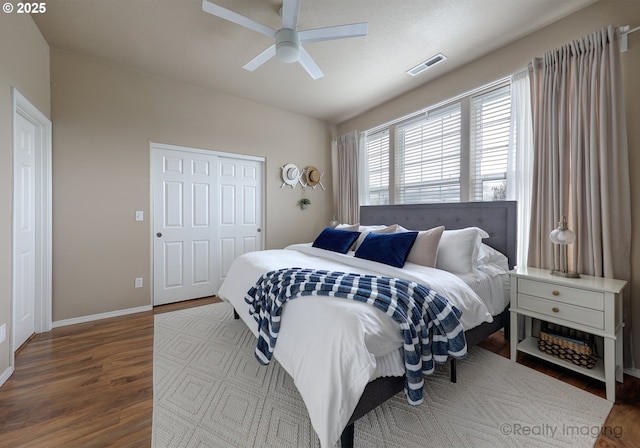 bedroom featuring a ceiling fan, wood finished floors, visible vents, and baseboards