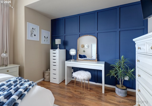 bedroom featuring wood finished floors and a decorative wall