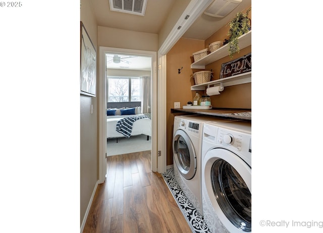 clothes washing area with visible vents, wood finished floors, baseboards, laundry area, and washing machine and clothes dryer