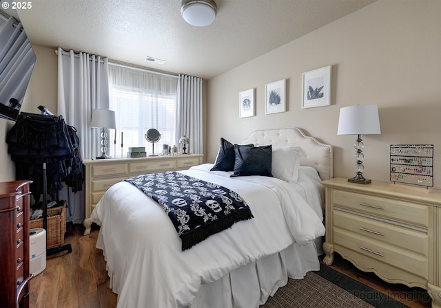 bedroom with visible vents, a textured ceiling, and wood finished floors