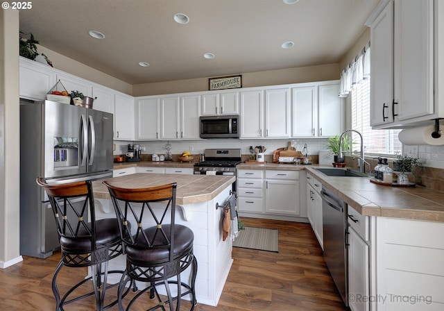 kitchen with a kitchen bar, a sink, a center island, appliances with stainless steel finishes, and white cabinets