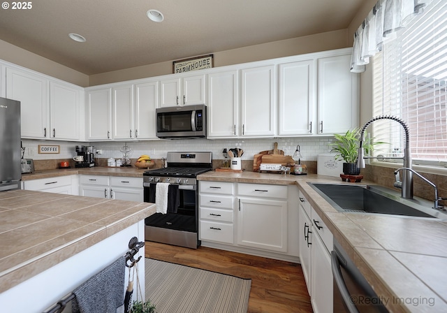 kitchen with a sink, tasteful backsplash, appliances with stainless steel finishes, and white cabinetry