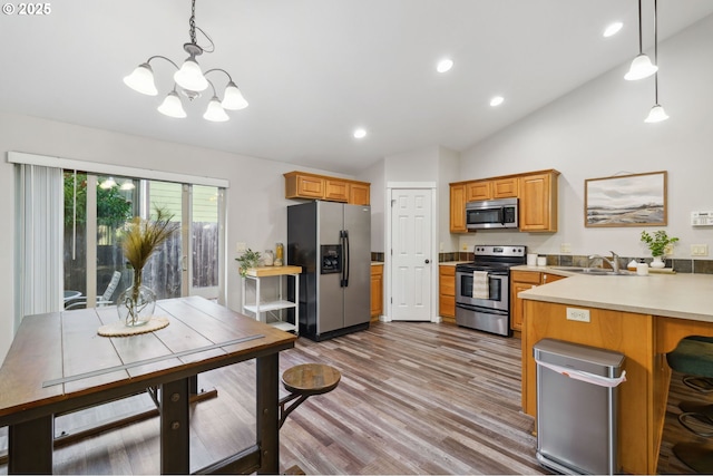 1230 W Fairview Dr, Springfield, OR 97477 - kitchen with stainless steel appliances, vaulted ceiling, a chandelier, wood finished floors, and a peninsula