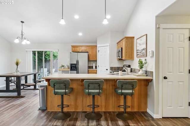 1230 W Fairview Dr, Springfield, OR 97477 - kitchen with appliances with stainless steel finishes, a peninsula, light countertops, dark wood-style flooring, and decorative light fixtures