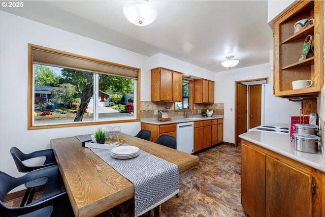 kitchen featuring a sink, decorative backsplash, white dishwasher, and light countertops