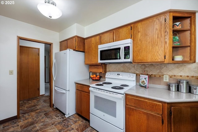 kitchen with brown cabinets, white appliances, light countertops, stone finish floor, and backsplash