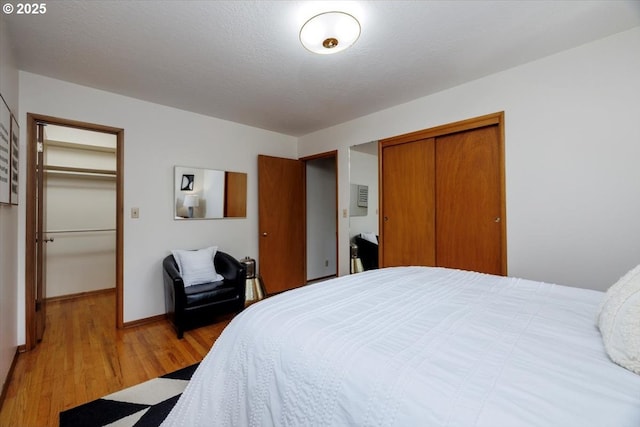 bedroom with a closet, light wood-style flooring, and baseboards