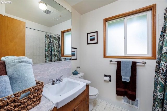 bathroom with baseboards, plenty of natural light, toilet, and visible vents