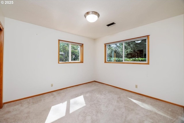 unfurnished room featuring baseboards, visible vents, and light carpet