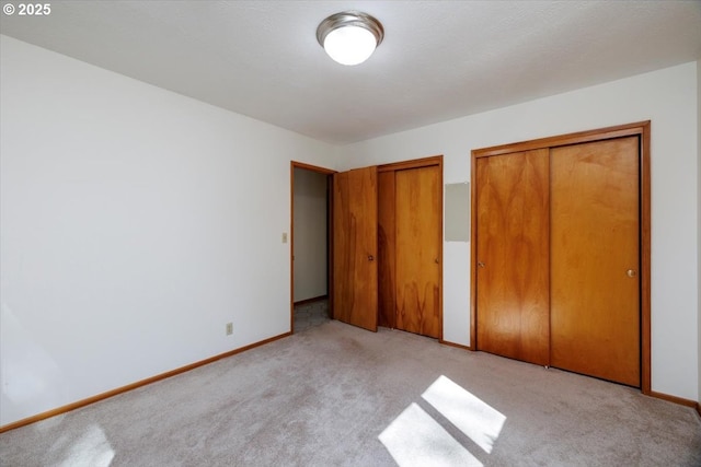 unfurnished bedroom with carpet floors, baseboards, and multiple closets