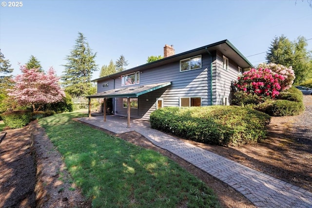 back of house featuring a patio area, a yard, and a chimney