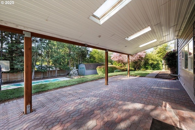 view of patio / terrace with a fenced in pool, a fenced backyard, an outbuilding, and a storage shed