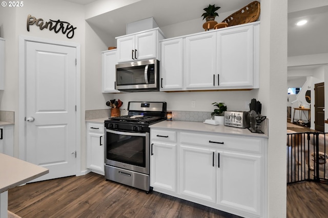 kitchen featuring stainless steel appliances, light countertops, dark wood finished floors, and white cabinetry