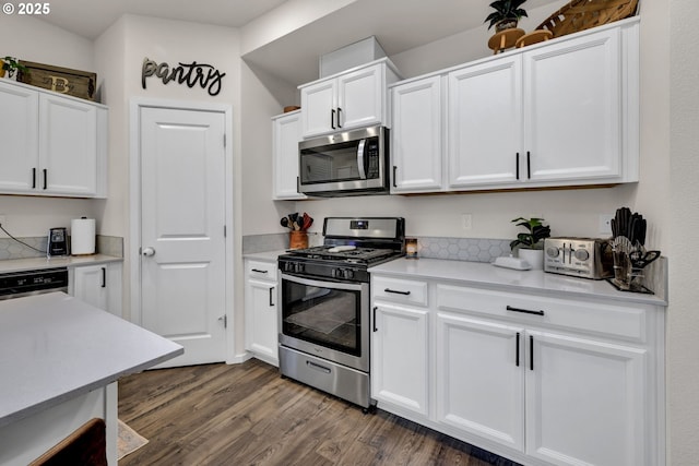 kitchen with dark wood-style floors, stainless steel appliances, light countertops, and white cabinets