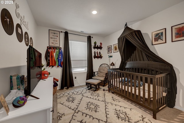 bedroom with visible vents, light colored carpet, and a crib