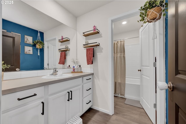 full bath featuring shower / tub combo, wood finished floors, vanity, and baseboards