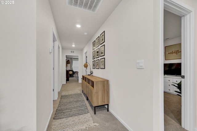 corridor with light carpet, baseboards, and visible vents