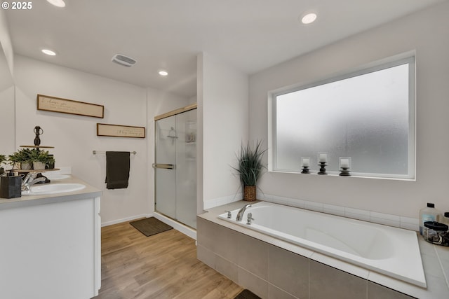 bathroom with double vanity, visible vents, a stall shower, a sink, and wood finished floors