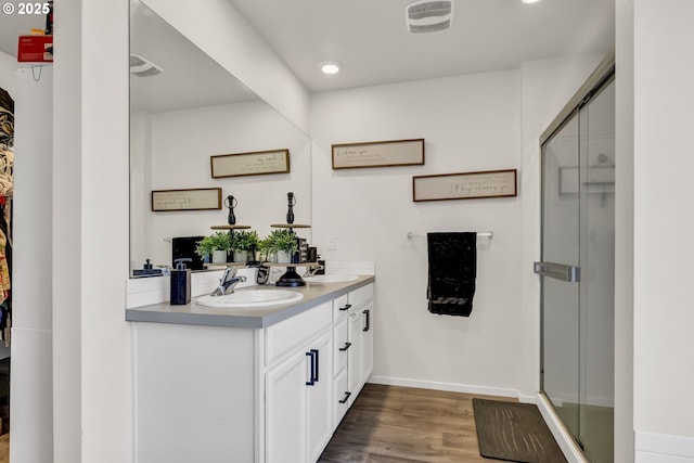 bathroom with visible vents, a sink, a shower stall, and wood finished floors