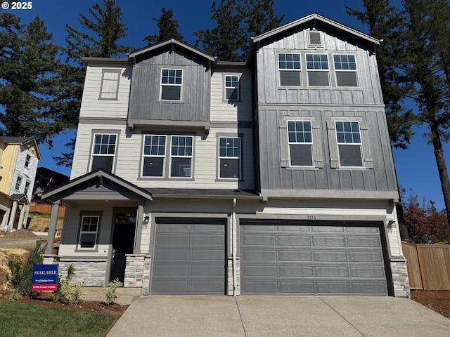 townhome / multi-family property with concrete driveway, stone siding, a garage, and board and batten siding