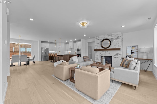 2134 Eleanor Rd, West Linn, OR 97068 - living room featuring light wood-type flooring, a chandelier, a fireplace, recessed lighting, and baseboards