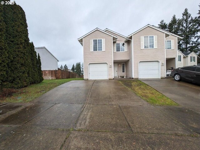 traditional-style home with a garage, driveway, and fence