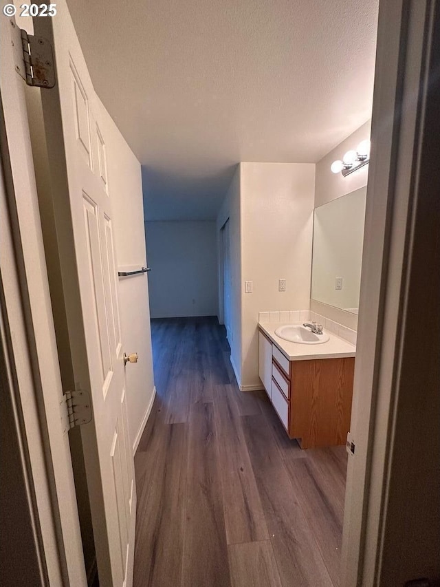 bathroom with baseboards, vanity, a textured ceiling, and wood finished floors