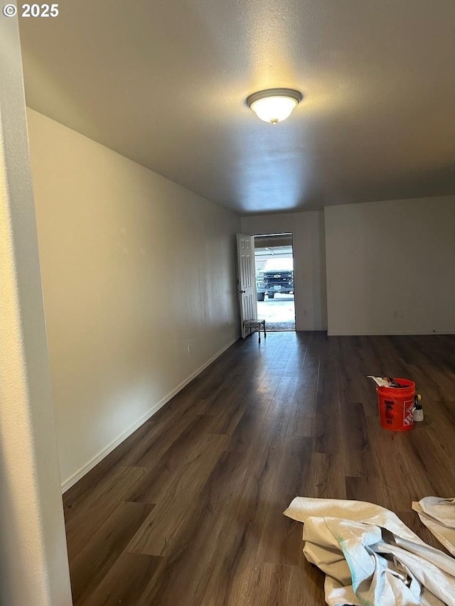 interior space with dark wood-style flooring, a textured ceiling, and baseboards