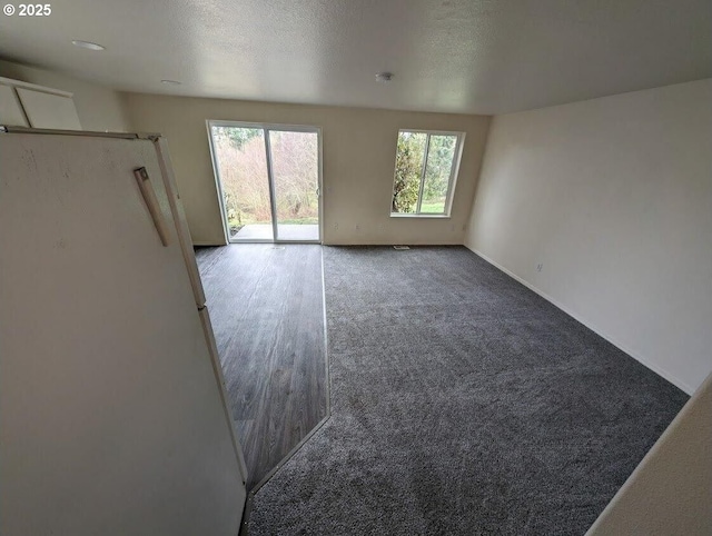 spare room with a textured ceiling, carpet floors, and baseboards