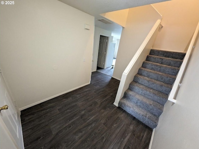 stairway featuring visible vents, baseboards, and wood finished floors