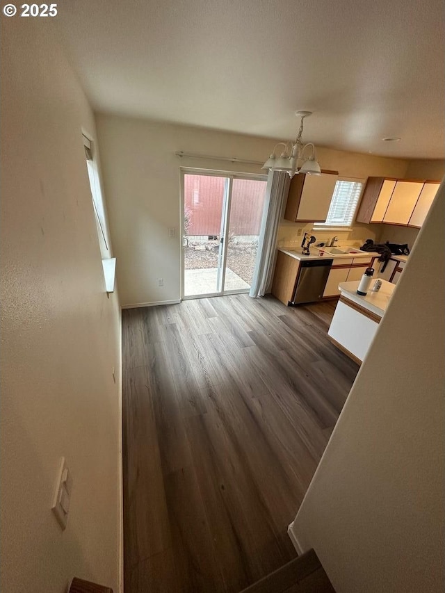 kitchen featuring dark wood-style flooring, light countertops, a sink, dishwasher, and baseboards