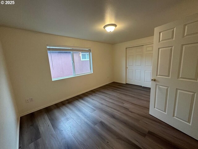 unfurnished bedroom featuring dark wood-style flooring and baseboards