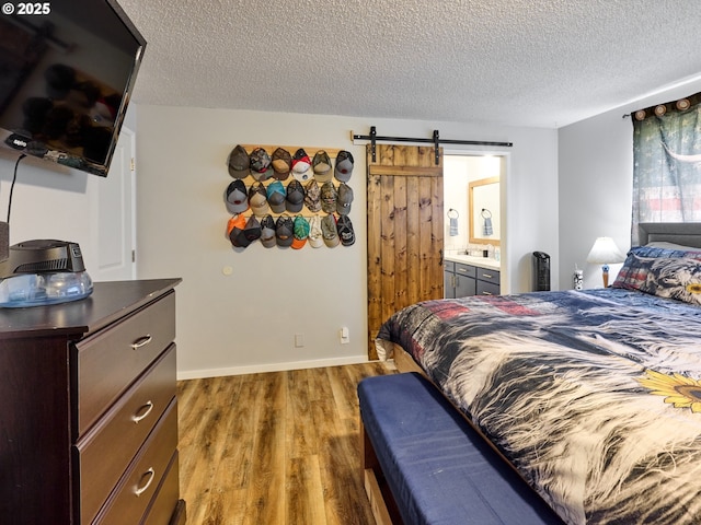 1301 49th Ave, Salem, OR 97317 - bedroom with wood finished floors, a textured ceiling, a barn door, and ensuite bath