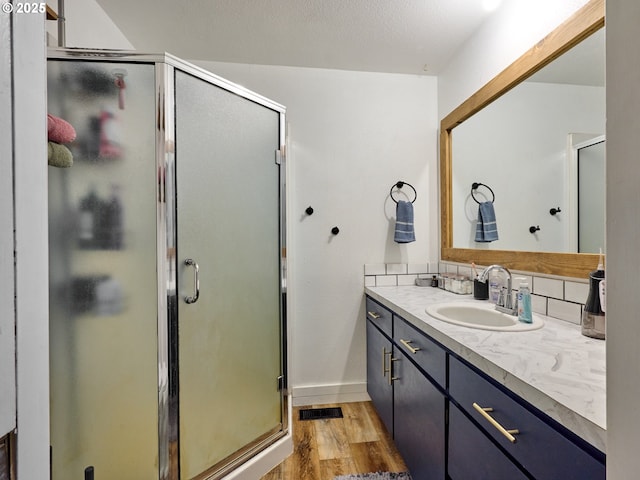 1301 49th Ave, Salem, OR 97317 - full bath with vanity, wood finished floors, a shower stall, decorative backsplash, and baseboards
