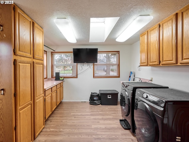 1301 49th Ave, Salem, OR 97317 - laundry room with cabinet space, washing machine and clothes dryer, a textured ceiling, light wood-style flooring, and baseboards