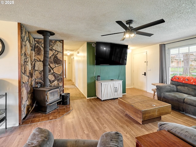 1301 49th Ave, Salem, OR 97317 - living room featuring a textured ceiling, a wood stove, ceiling fan, light wood finished floors, and baseboards
