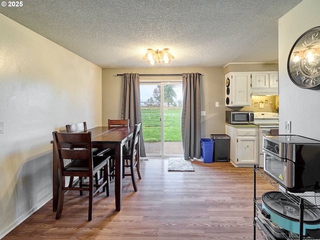 1301 49th Ave, Salem, OR 97317 - dining area featuring wood finished floors, a textured ceiling, a chandelier, and baseboards