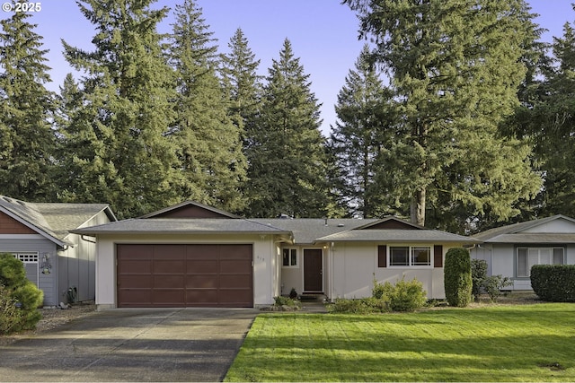 ranch-style house featuring an attached garage, concrete driveway, and a front yard