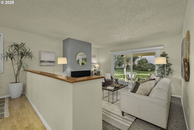 living area with a textured ceiling, baseboards, and wood finished floors