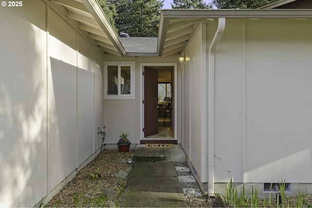 view of exterior entry with a shingled roof