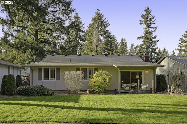 rear view of house featuring a patio area, a chimney, and a yard