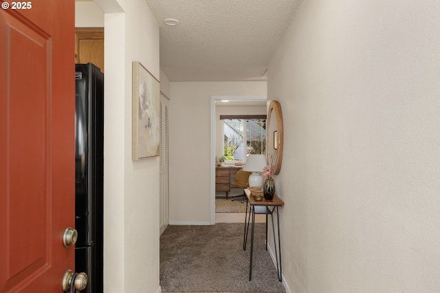 hall featuring carpet floors, a textured ceiling, and baseboards