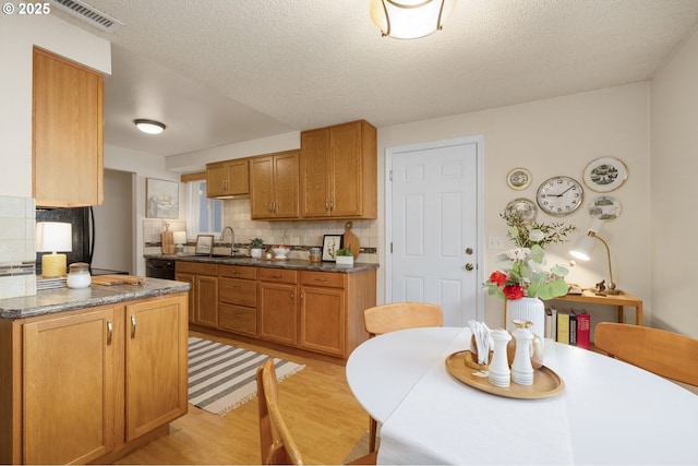 kitchen featuring tasteful backsplash, a sink, visible vents, and light wood-style floors